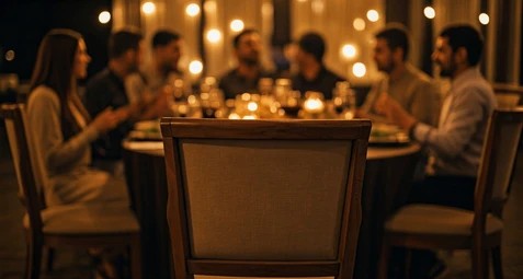 “Long dining table in warm light; an empty chair at the far end.”