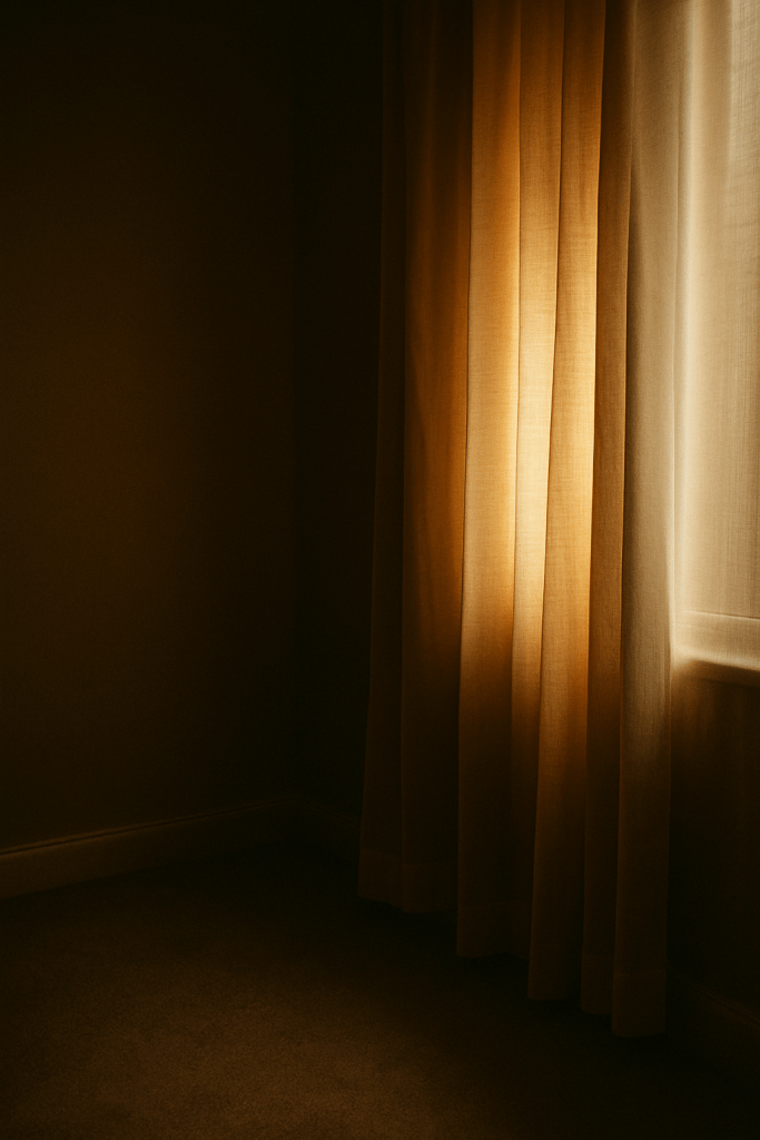 Sunlight filtering softly through sheer curtains into a dim, quiet room, creating a gentle, reflective atmosphere.
