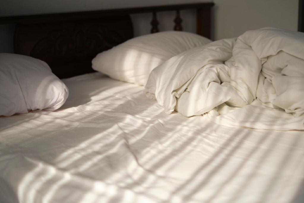 A softly lit bedroom with sunlight coming through a window, creating a calm and restful atmosphere.