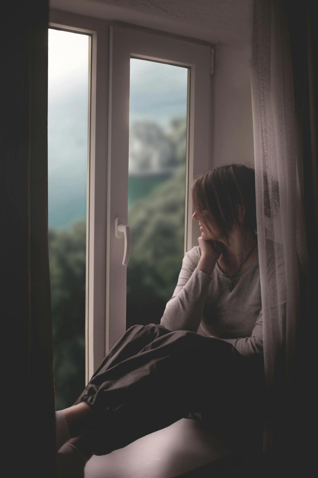 Soft side-profile of a woman reading by a window, in warm, quiet light.